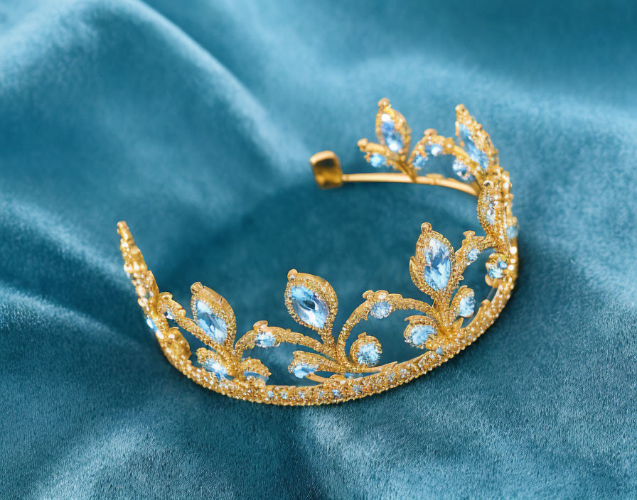 Golden tiara with crystals and blue gemstones on blue velvet fabric