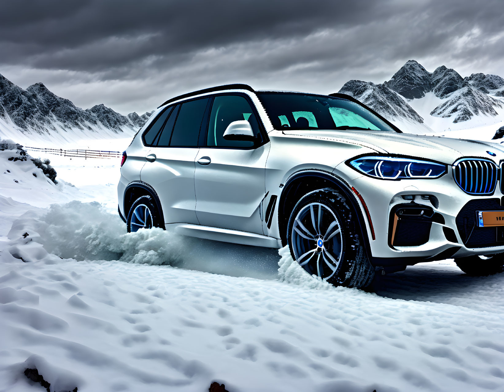 White SUV parked in snow with mountains and cloudy sky