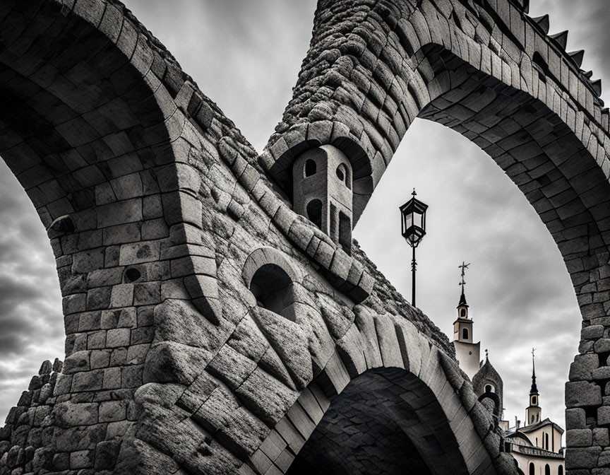 Ancient stone aqueduct with arches and church spires under cloudy sky