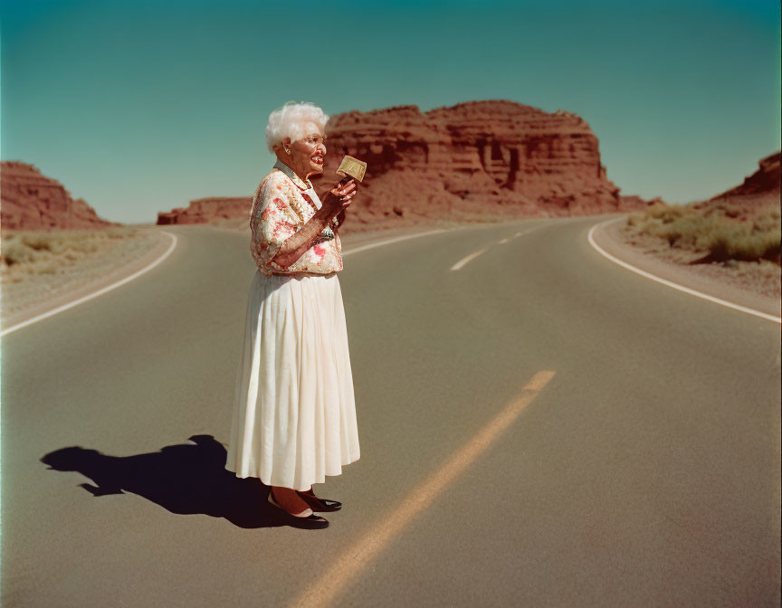 Elderly woman with Bible on deserted road with rock formation