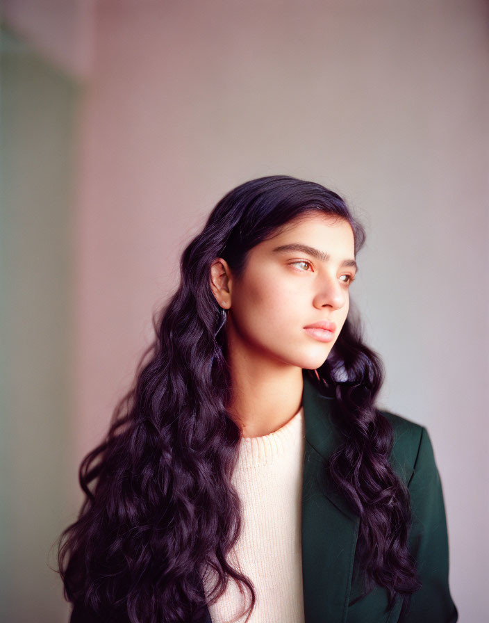 Serene woman with long wavy hair in white top and green blazer