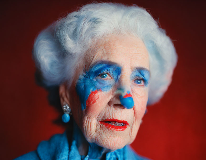 Elderly lady with striking blue makeup on red background