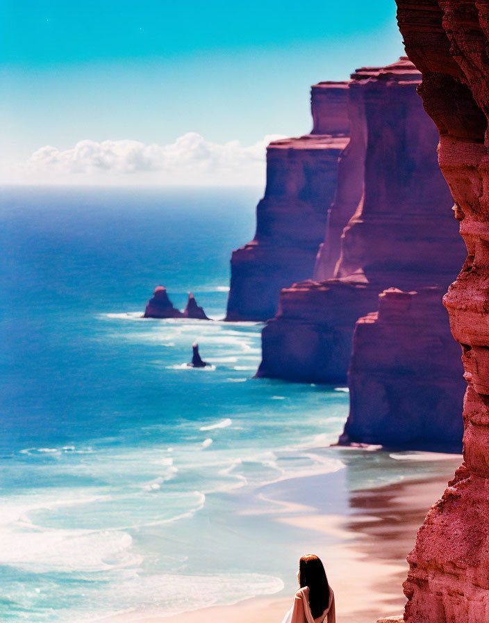 Serene beach scene with towering red cliffs under clear blue sky