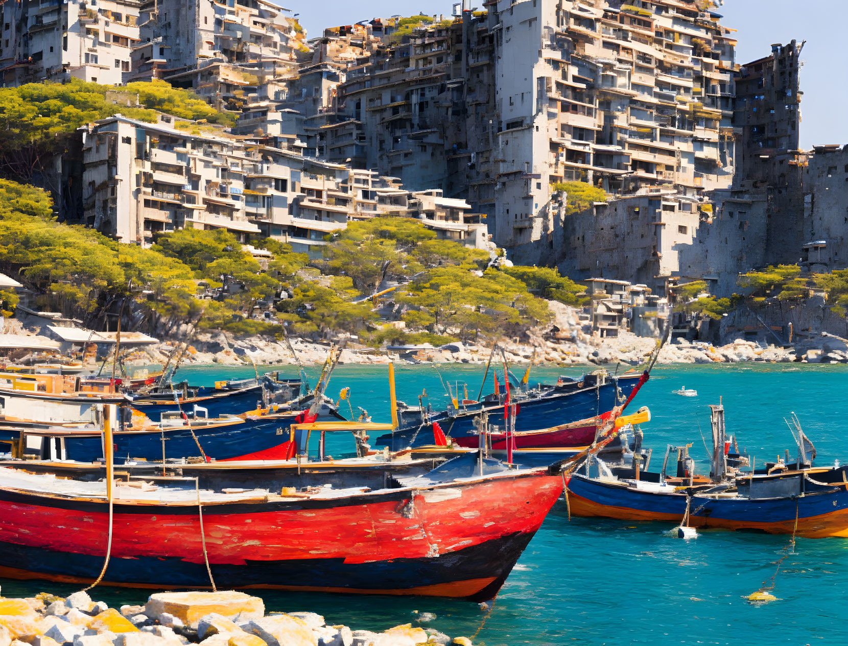 Vibrant fishing boats in blue bay with rundown high-rises on rocky coast