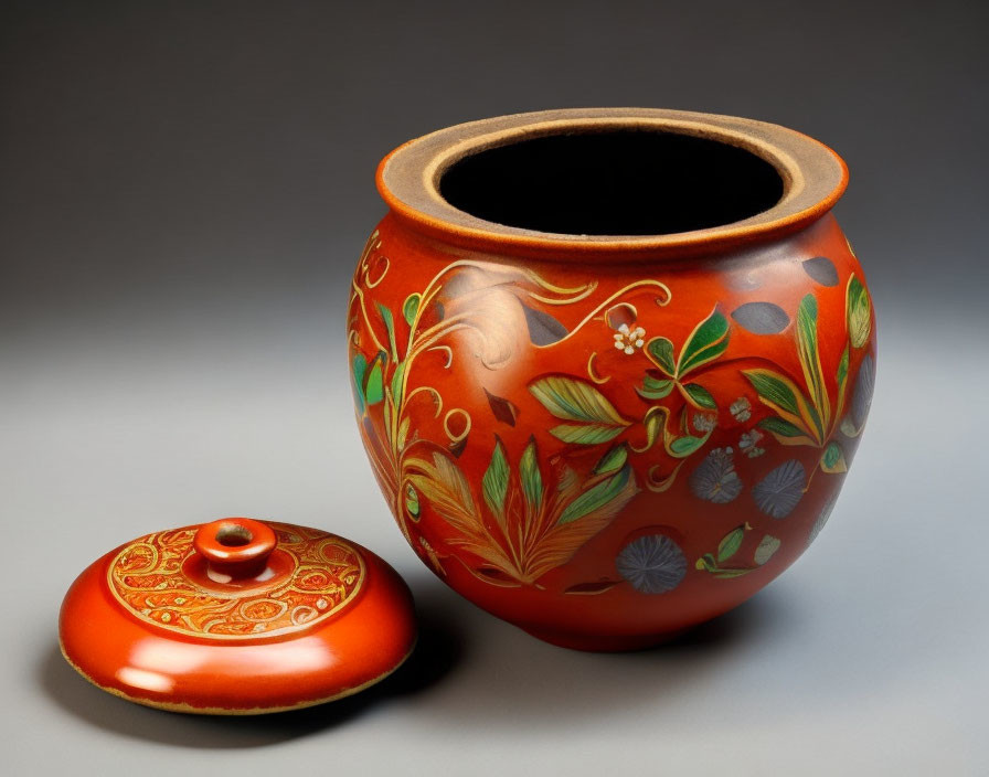 Orange Ceramic Pot with Floral Motifs and Lid on Grey Background