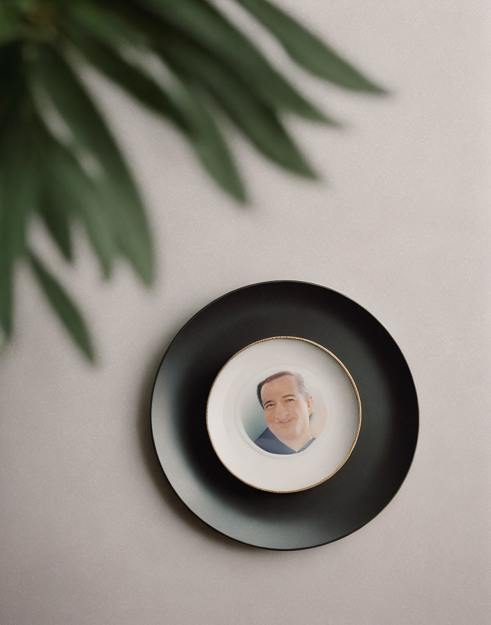 Monochrome portrait of a smiling man on plate with green plant leaf