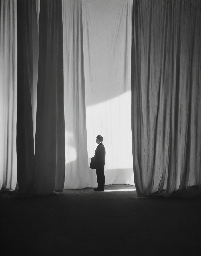 Silhouetted figure amid billowing curtains with dramatic lighting.