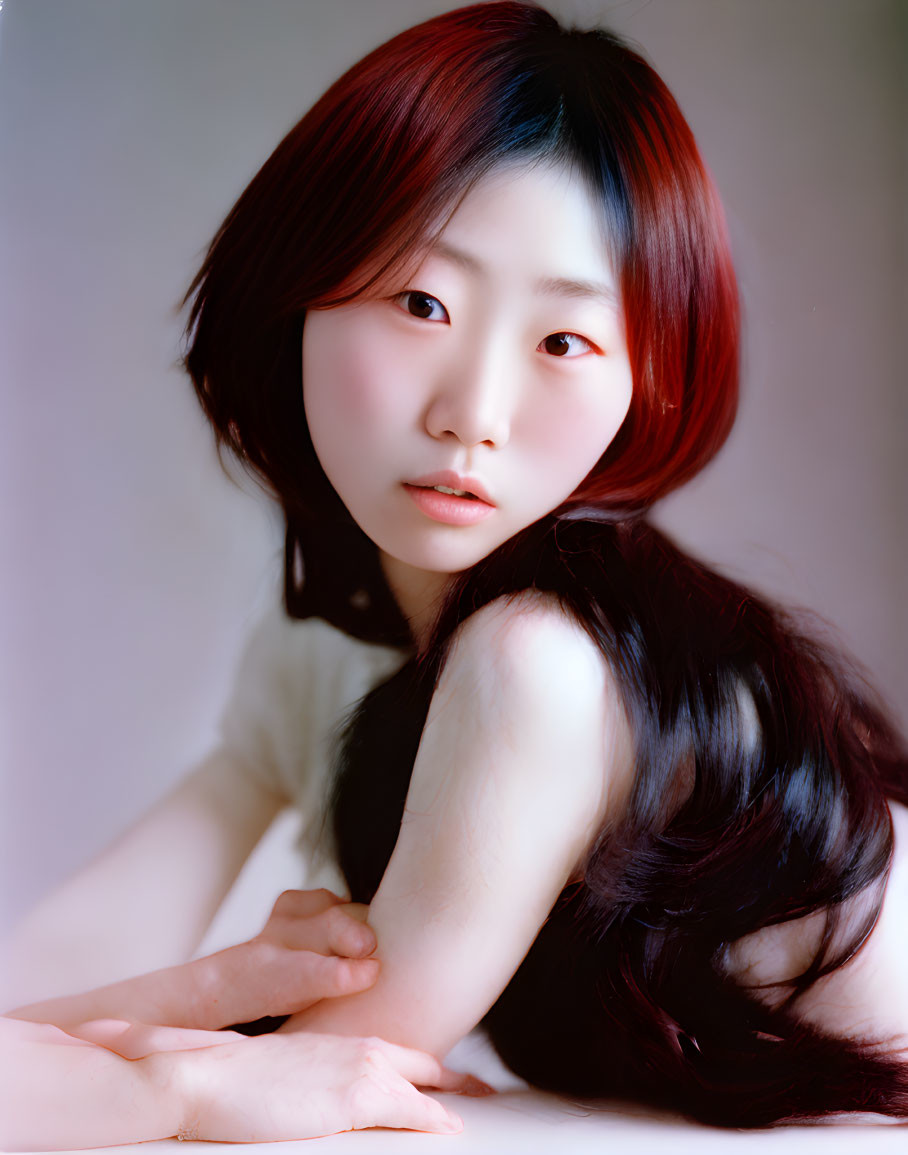 Portrait of woman with dark hair and red highlights gazing at camera