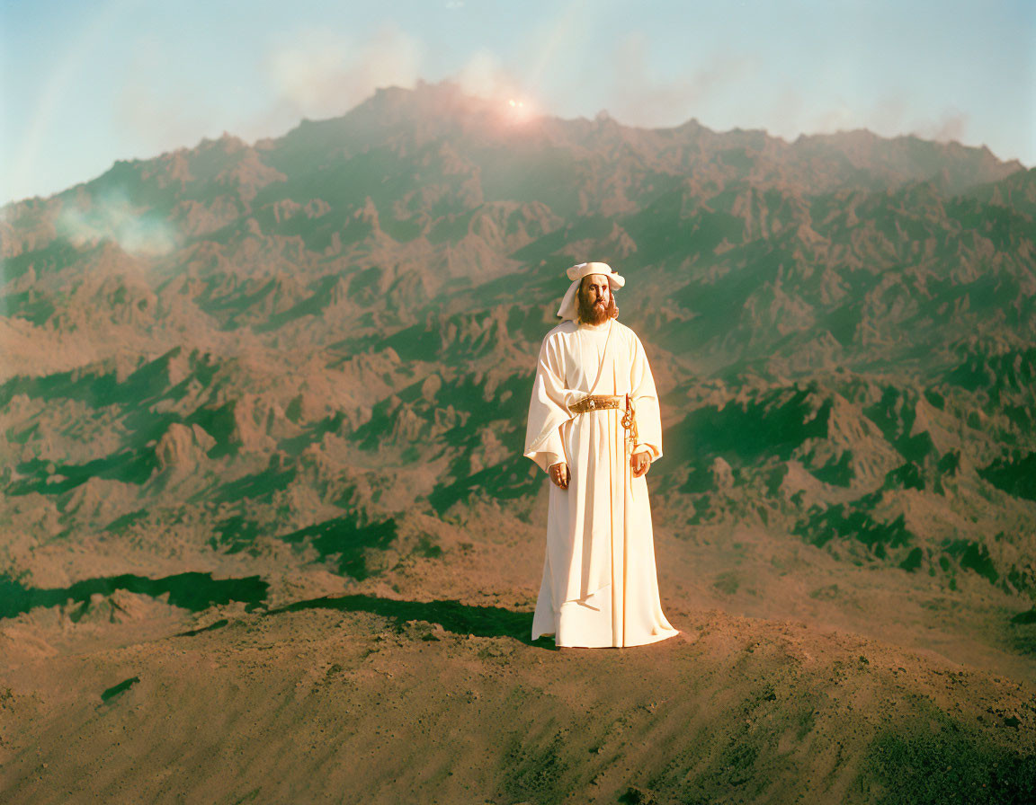 Traditional White Attire Man in Front of Sunlit Mountain Range