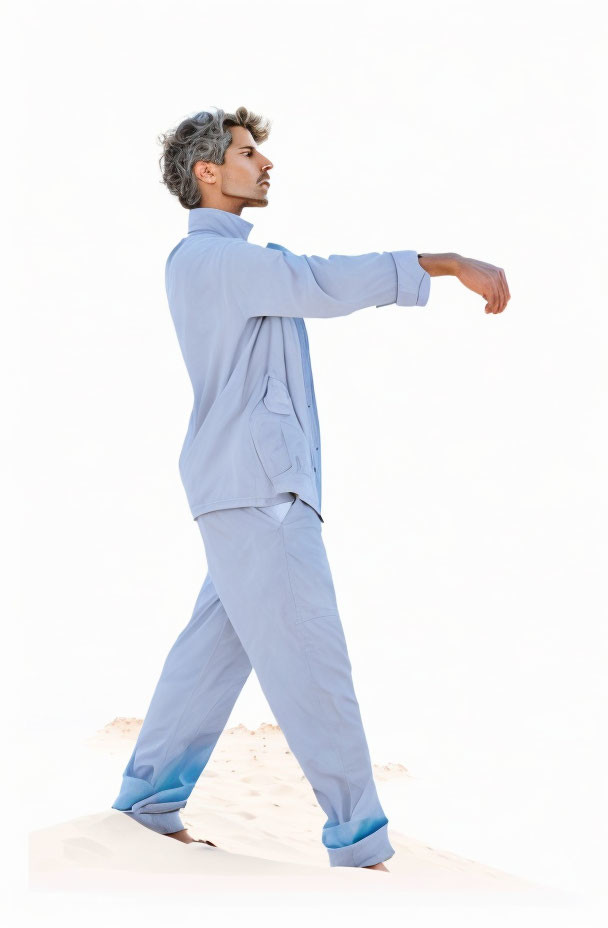 Grey-Haired Man in Light Blue Outfit Posing Sideways on White Background