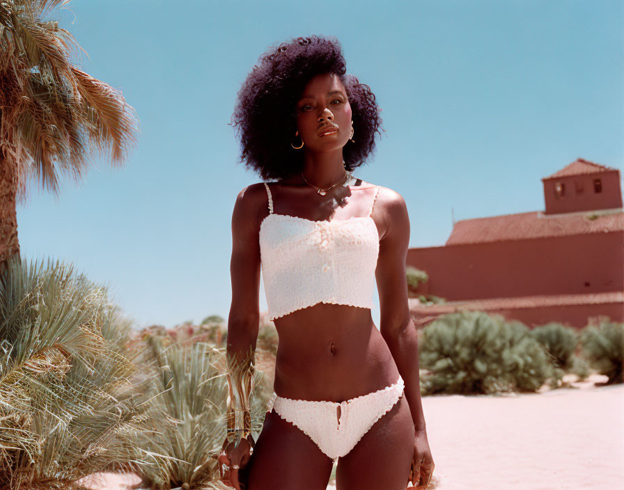 Dark Curly-Haired Woman in White Swimsuit Outdoors with Clear Sky