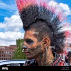 Vibrant mohawk hairstyle and face paint against city backdrop