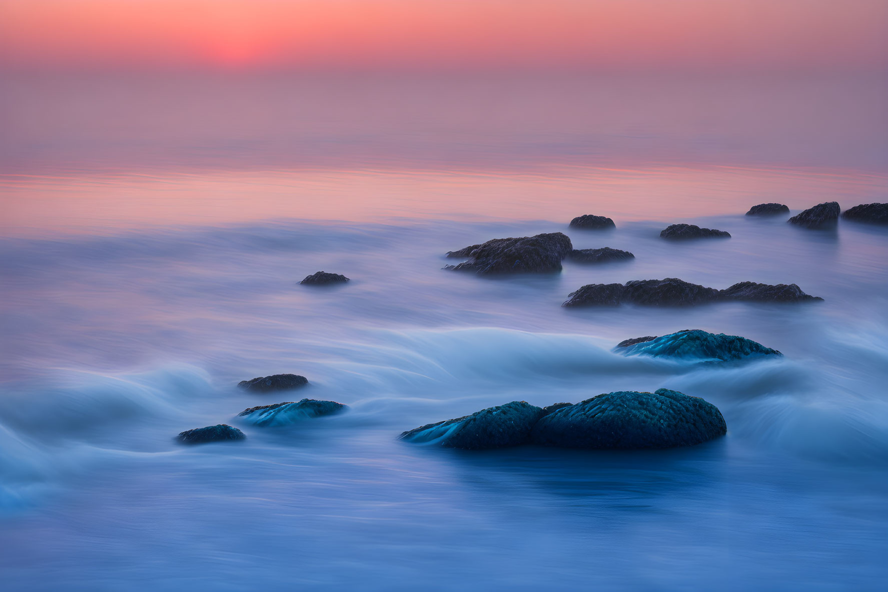 Tranquil sunset seascape with soft waves and blue-pink hues