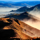 Autumn foliage on rolling hills under misty sunlight: blue and golden layers