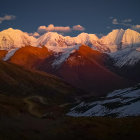 Snow-capped peaks and dark clouds in dramatic mountain landscape with winding river.