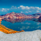 Snow-covered mountain lake under blue sky with clouds