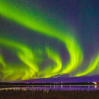 Stunning green and purple aurora borealis over snow-covered mountains