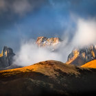 Sunlit rolling hills and mist-covered mountain peaks under a dramatic sky