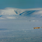 Snow-covered hills, hay bales, and mountains in panoramic winter landscape