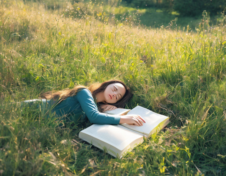 Person resting in grassy field with head on open book.