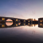 Vibrant surreal artwork of town, bridge, water, sky, and sun.