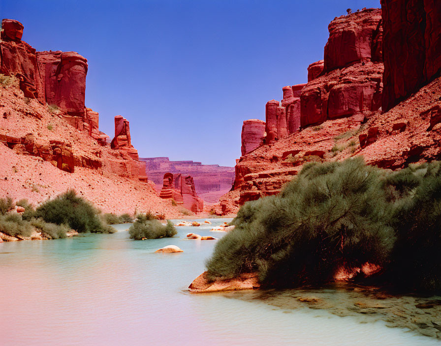 Tranquil turquoise river in red sandstone canyon under clear blue sky