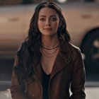 Blonde woman with blue eyes in leather jacket against dusk backdrop