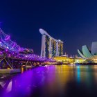 Futuristic night cityscape with organic buildings, waterbody, and starry sky