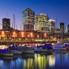 Cityscape with illuminated buildings reflected in water at twilight