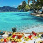 Tropical breakfast spread by infinity pool overlooking beach