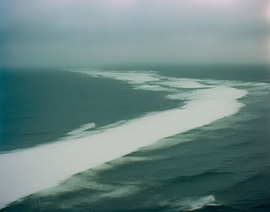 Misty seascape with white foamy wave in dark water