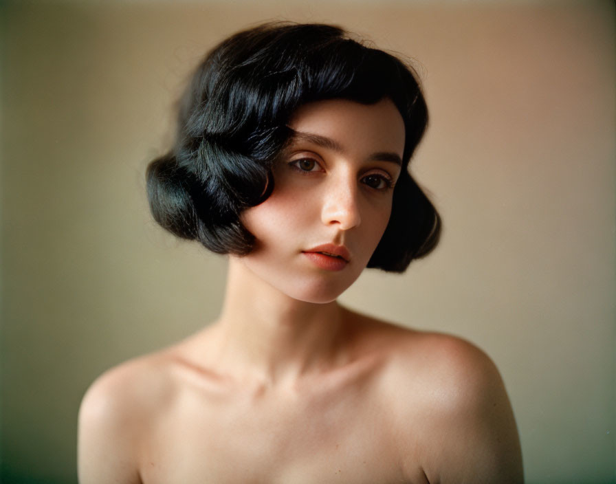 Portrait of person with shoulder-length black hair and bangs, looking sideways with contemplative expression