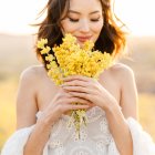 Illustrated girl with wavy hair holding yellow flowers in sunlit field