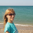 Blonde woman with sunglasses on beach with ocean and cloudy sky