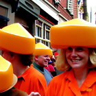 Group of People in Orange Outfits with Cheese-Shaped Hats Socializing