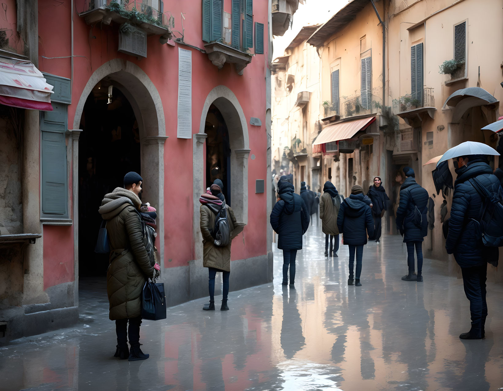 Group of people in winter coats with umbrellas on wet cobblestone street