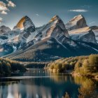 Snow-capped mountains and forest lake at sunset with golden sky