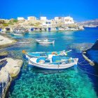 Tranquil painting of three boats near coastal village