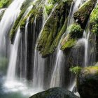 Tranquil waterfall over mossy cliffs in lush greenery