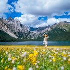 Couple walking in picturesque meadow with flowers and mountains