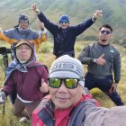 Smiling group takes selfie on mountain with motorcycles and helicopter