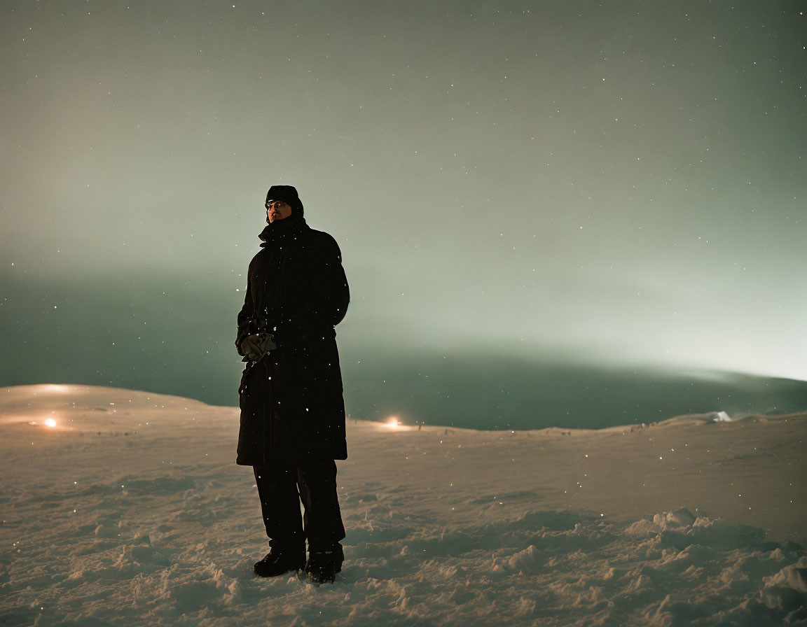 Person in Black Coat Standing on Snowy Hill at Night Under Starry Sky