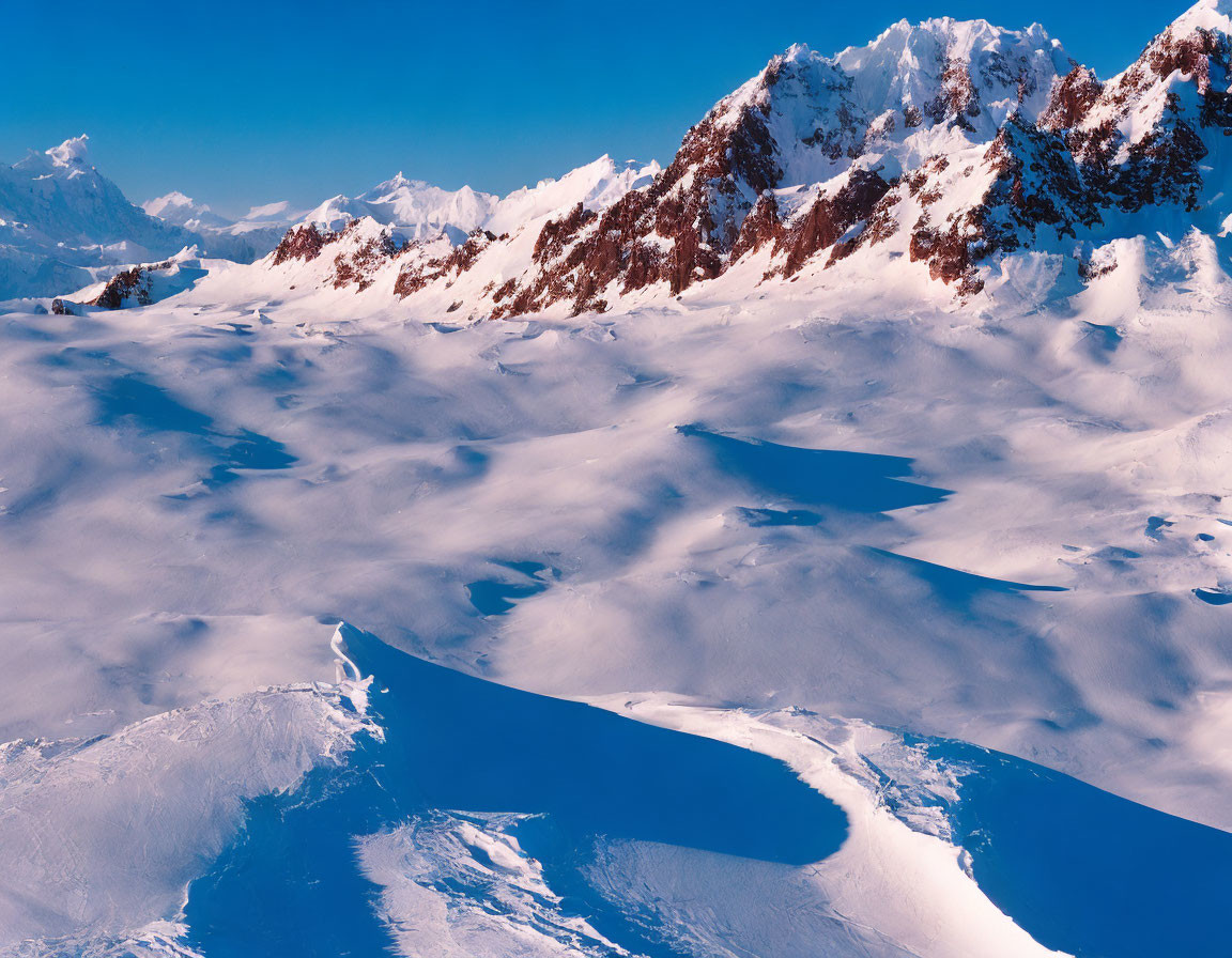 Snow-covered Mountain Range with Rugged Peaks and Blue Shadows