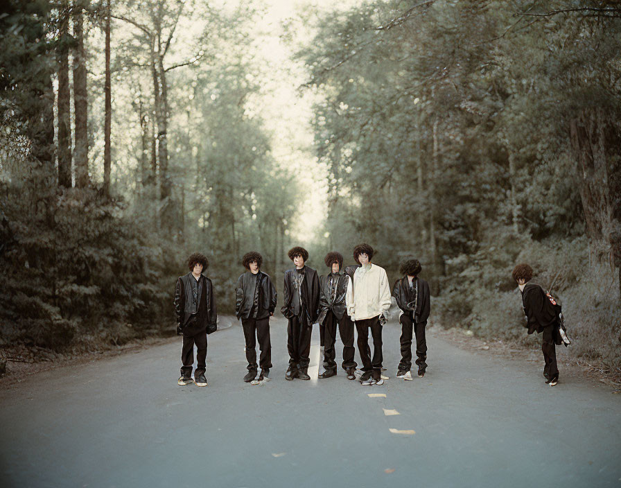 Group of Seven Individuals in Dark Clothing on Forest Road