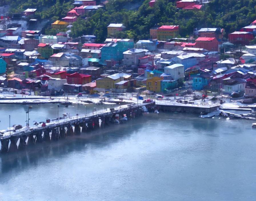 Colorful Coastal Town with Pier and Greenery Under Hazy Sky