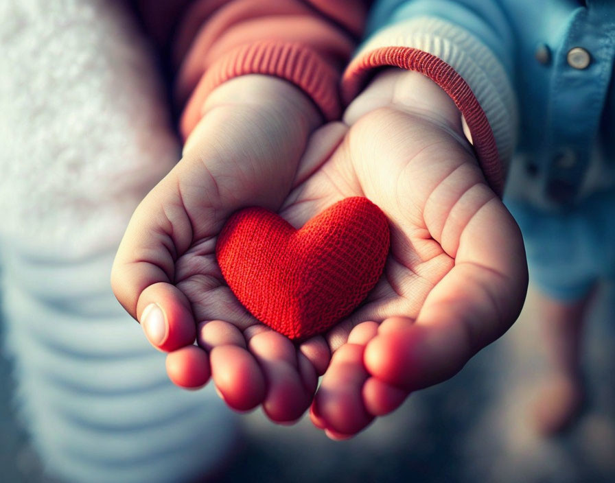 Red Knitted Heart Held by Two Hands with Soft Focus Background