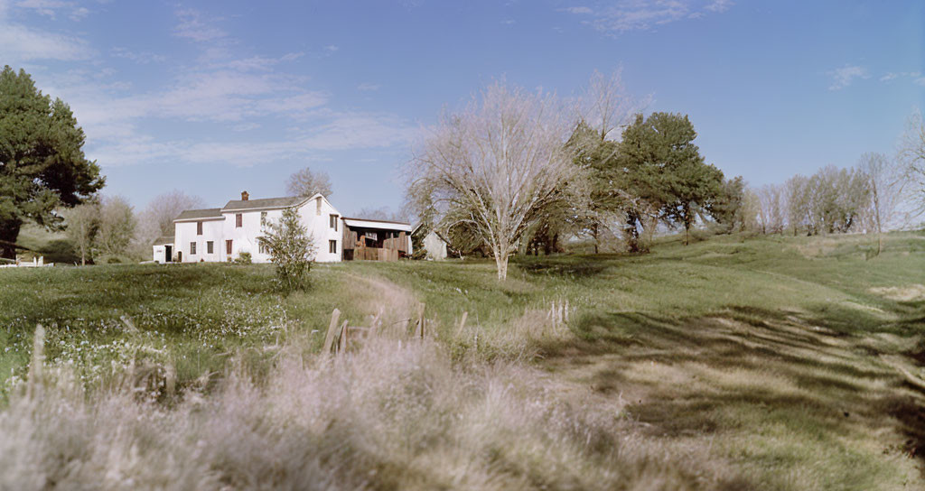 Serene rural landscape with white house, green hills, trees