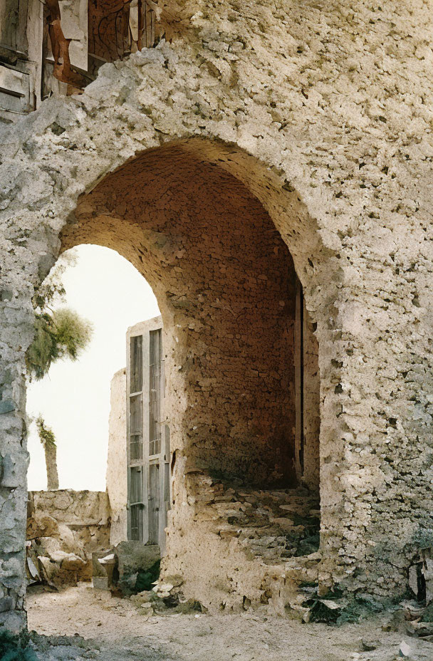 Ancient stone archway with remnants of doorframe and tree view