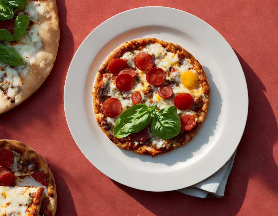 Pepperoni pizza with melted cheese and basil on white plate