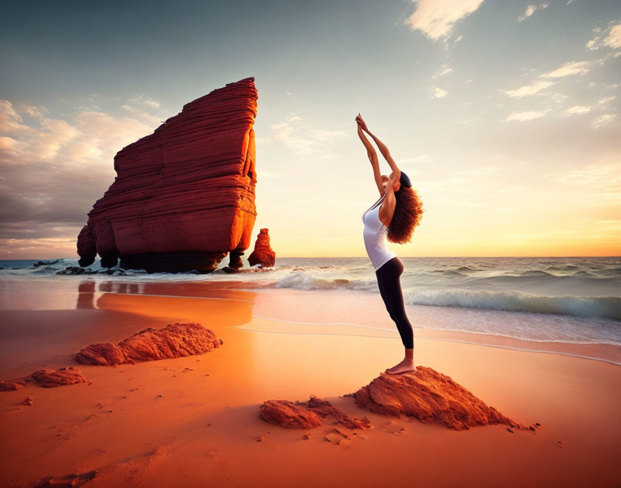 Yoga practice on beach at sunset with rock formation and waves